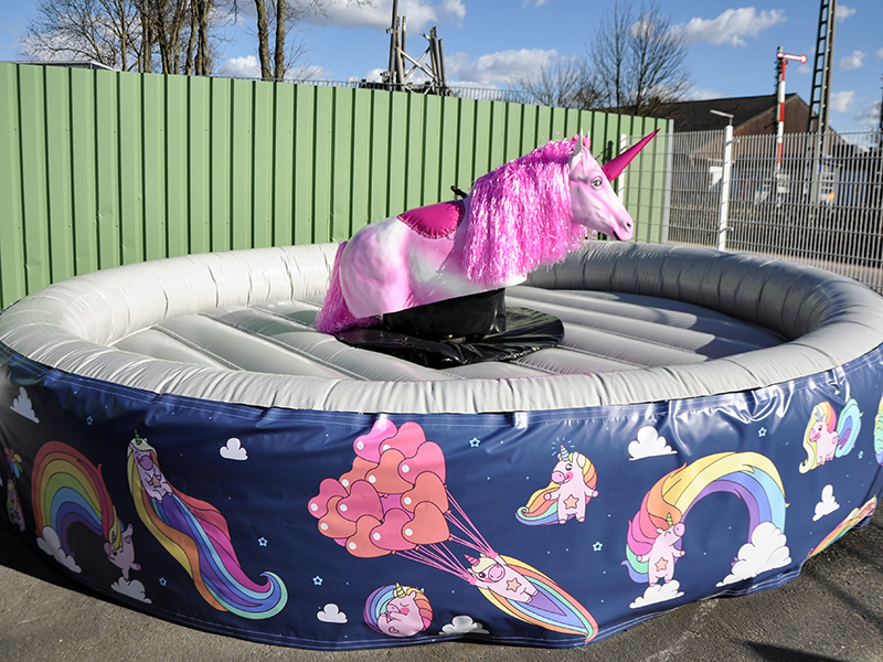 Aufblasbares Rodeo-Einhorn mit Regenbogenmotiv auf einer runden Luftkissenmatte