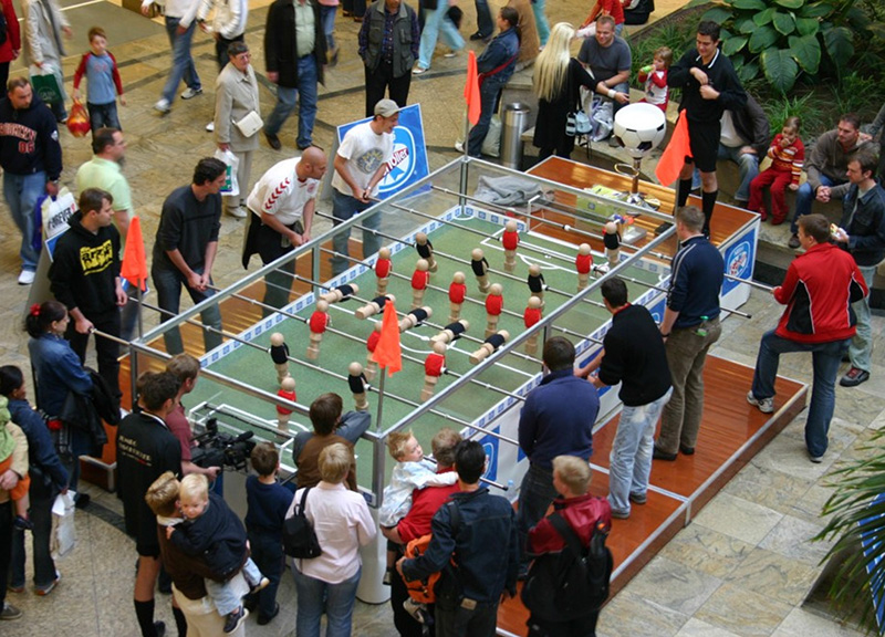 Übergroßer Tischkicker auf einem Stadtfest, Erwachsene und Kinder spielen gleichzeitig