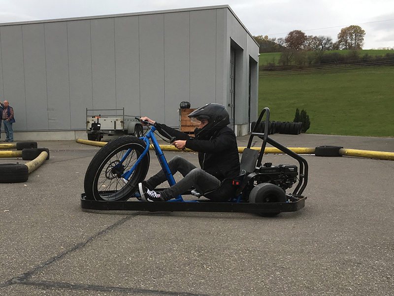 Fahrer driftet mit einem Drift-Trike über eine abgesteckte Asphaltbahn