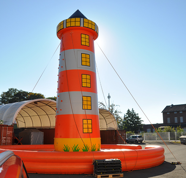 Aufblasbarer Kletterturm im Leuchtturm-Design in Rot und Weiß auf einem Freigelände