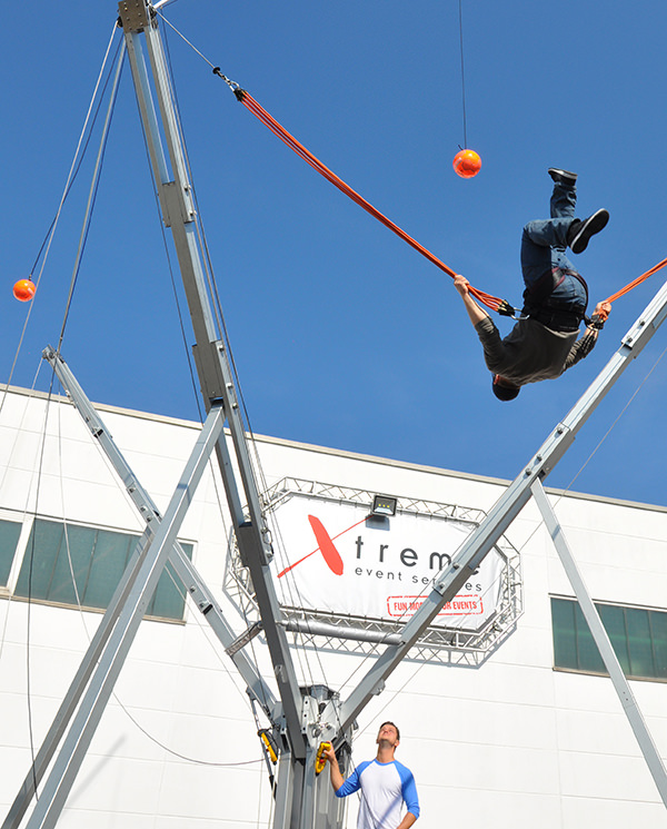 Teilnehmer schwebt am Bungee-Trampolin in der Luft und spielt einen Ball