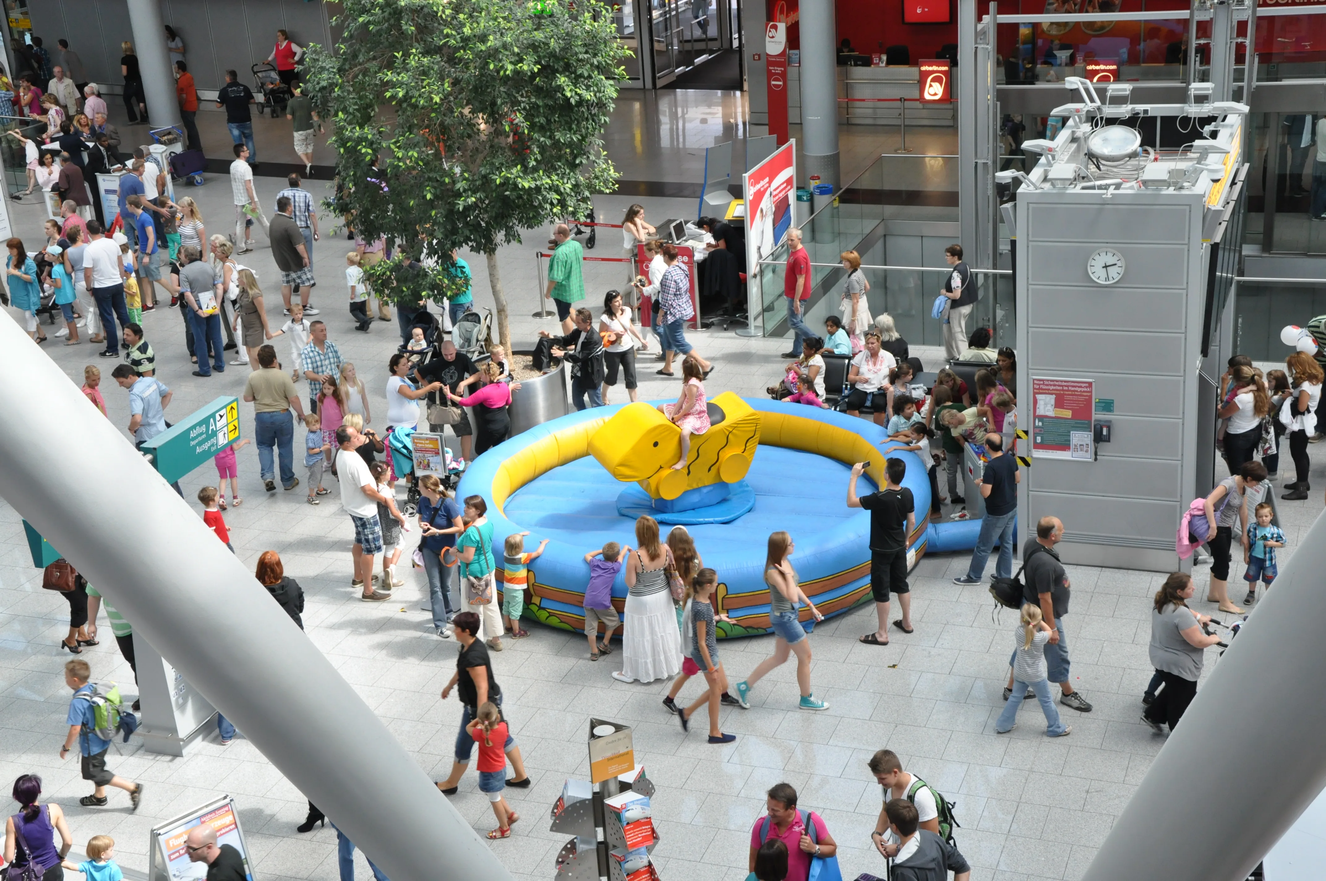 Busy pedestrian zone with bouncy castle, carousel and many visitors