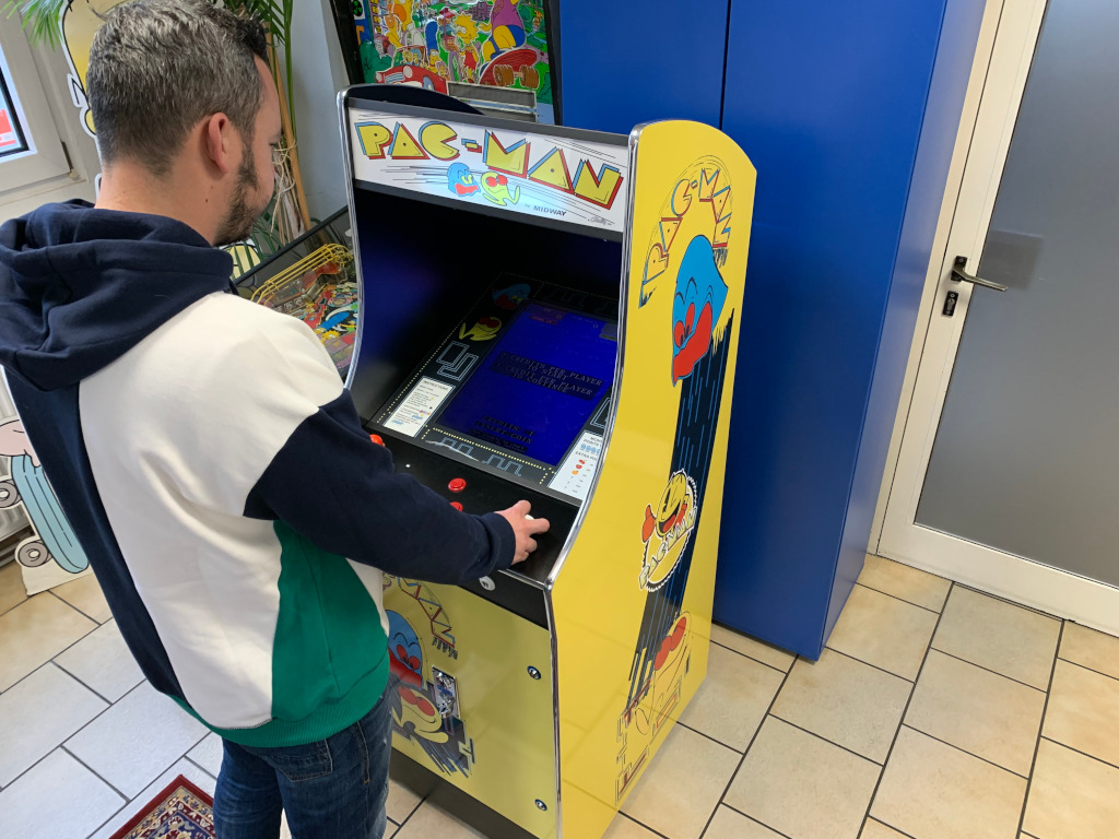 Mann spielt an einem gelben Pac-Man-Standautomaten