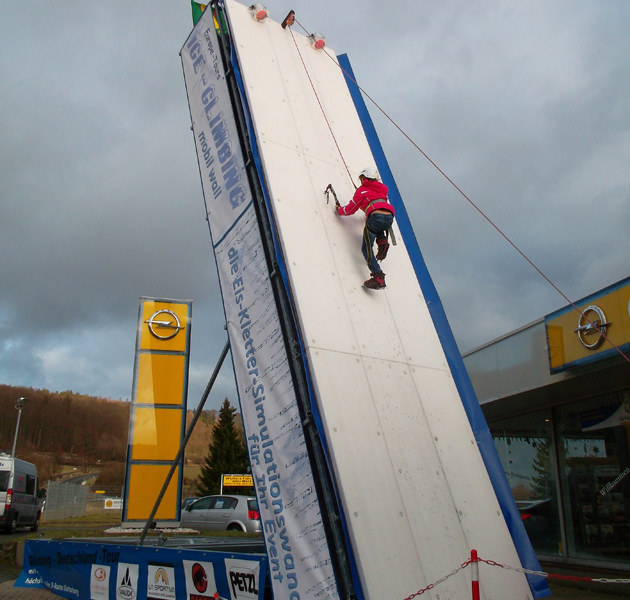 Kletterer mit Eispickeln an der hohen weißen Ice-Climbing-Wall